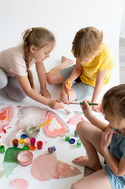 Foto gratuita niños de trabajo en equipo de cerca pintando juntos