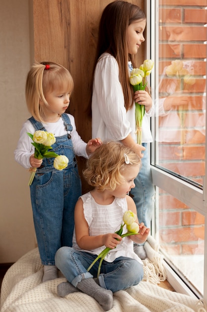 Niños en la ventana con flores.