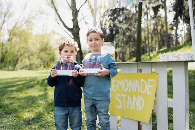 Niños de vista frontal con botellas de limonada