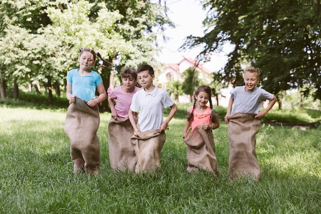 Foto gratuita niños de la vista frontal compitiendo en bolsas de arpillera