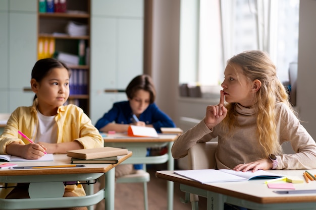 Foto gratuita niños de vista frontal haciendo trampa en la escuela