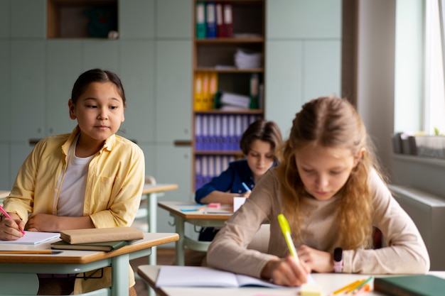 Foto gratuita niños de vista frontal haciendo trampa en la escuela