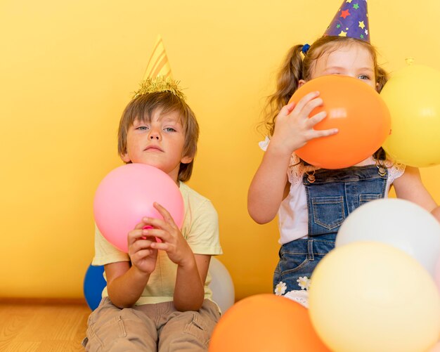 Niños de vista frontal jugando con globos en el interior