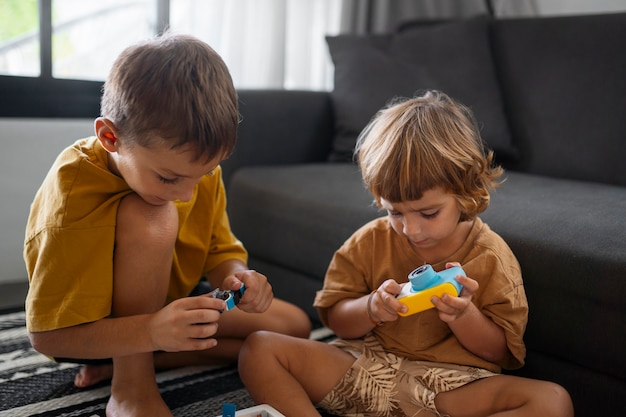 Foto gratuita niños de vista frontal jugando con juguetes en el interior