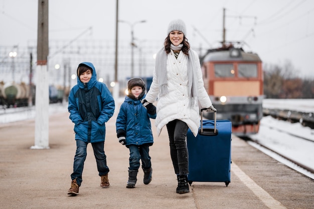 Niños de vista frontal y mujer en la estación de tren