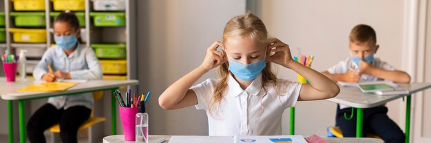 Niños de vista frontal protegiéndose con máscaras médicas