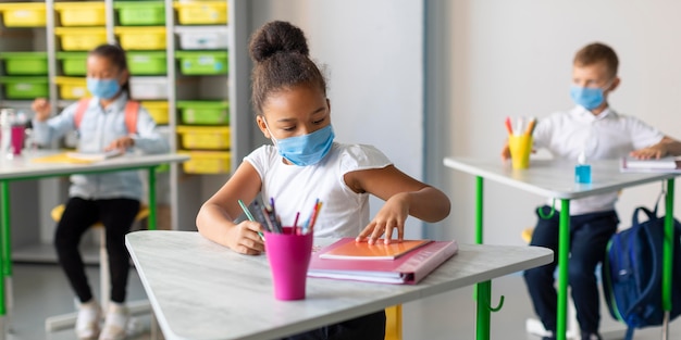 Foto gratuita niños de vista frontal protegiéndose con mascarillas