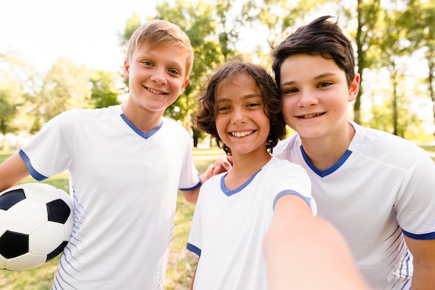 Niños de vista frontal en ropa deportiva de fútbol tomando un selfie