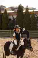 Foto gratuita niños de vista lateral aprendiendo a montar a caballo.