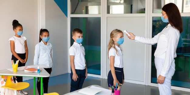 Foto gratuita niños de vista lateral esperando en línea para mediciones de temperatura