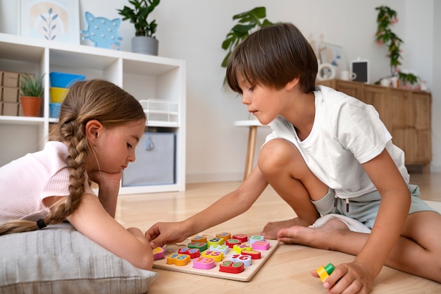 Foto gratuita niños de vista lateral haciendo rompecabezas juntos