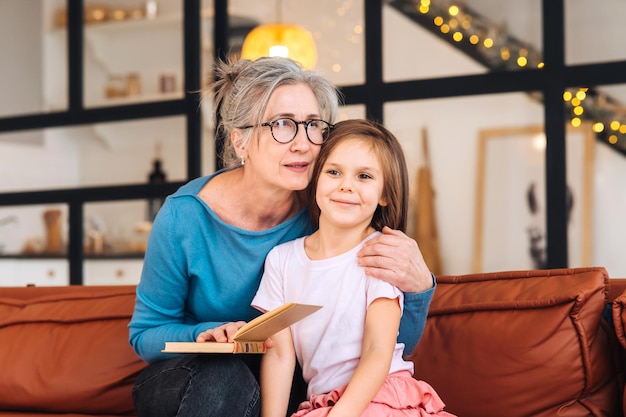 Niza anciana abuela leyendo una historia a su nieta