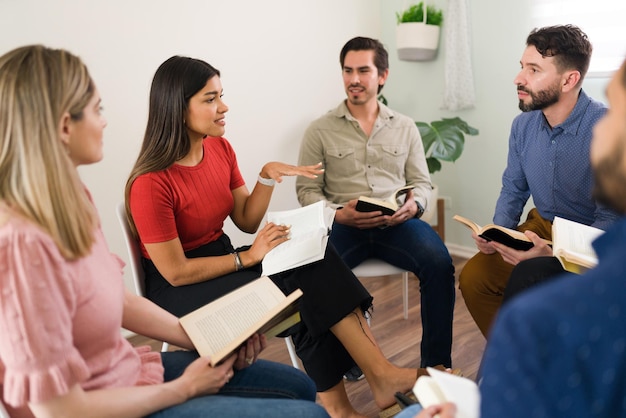 Este no es mi libro favorito. Atractiva mujer joven hablando de una novela con un grupo de diversas personas sentadas en círculo en un club de lectura