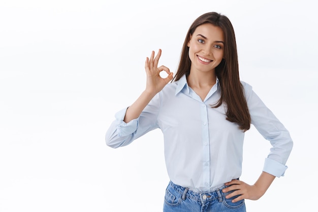 Foto gratuita no hay problema. una joven profesional confiada y relajada asegura que puede lidiar con cualquier cosa por su cuenta. una dama fuerte y empoderada en el trabajo muestra un gesto correcto y un fondo blanco sonriente y satisfecho.