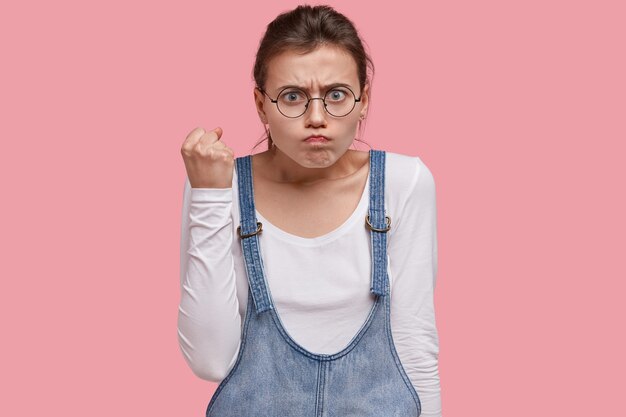 No juegues conmigo. El adolescente enojado indignado levanta el puño, frunce el ceño, se siente molesto, tiene expresión enojada, demuestra un gesto de amenaza