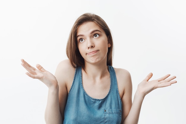 Foto gratuita no lo se, lo siento. atractiva chica caucásica morena divertida en ropa casual mirando a un lado con expresión incómoda, extendiendo las manos.