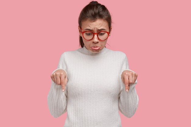 No me gusta esto. Mujer desesperada se enfurruña y frunce el ceño por la decepción y el arrepentimiento, indica en el piso, tiene tiempos difíciles, ve algo desagradable