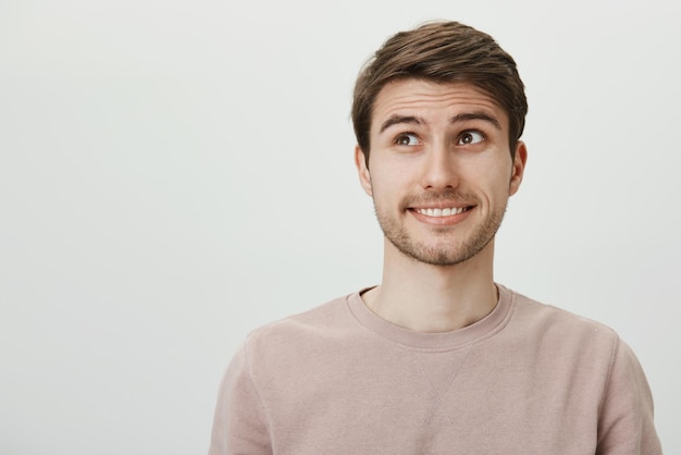 No me mires, no fue mi culpa. Chico caucásico guapo descuidado con cerdas levantando las cejas y mirando a un lado, sonriendo torpemente