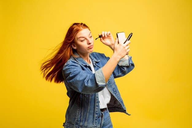 No necesitas una selfie para maquillarte. Retrato de mujer caucásica en espacio amarillo