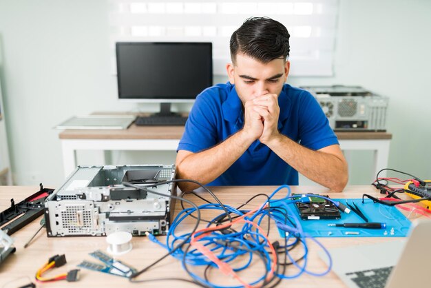 No se que hacer. Técnico preocupado que se siente confundido mientras mira los cables de una computadora y piensa cómo solucionarlo