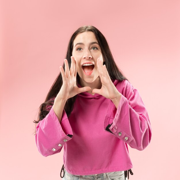 No te pierdas. Joven mujer casual gritando. Gritar. Mujer emocional llorando gritando en el espacio rosa. Retrato femenino de medio cuerpo