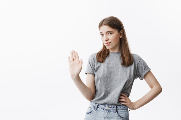 No voy a discutirlo. Retrato de una hermosa chica caucásica confiada con cabello castaño gesticulando con la mano, mostrando que no quiere escuchar a su novio que intenta explicar que no está engañando.