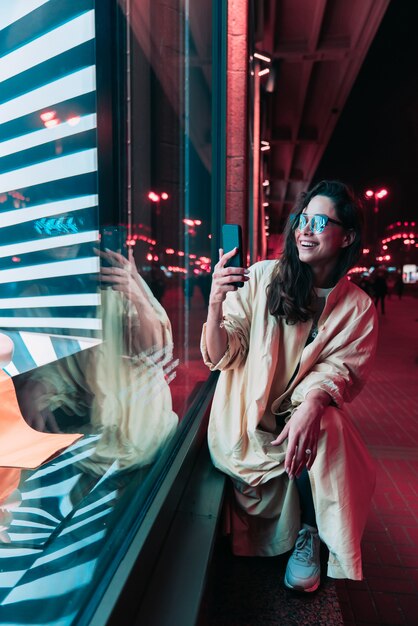 Noche en la ciudad, hermosa mujer entre luces rojas.