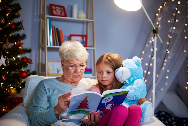 Noche de Navidad con abuela, libro de cuentos y osito de peluche.