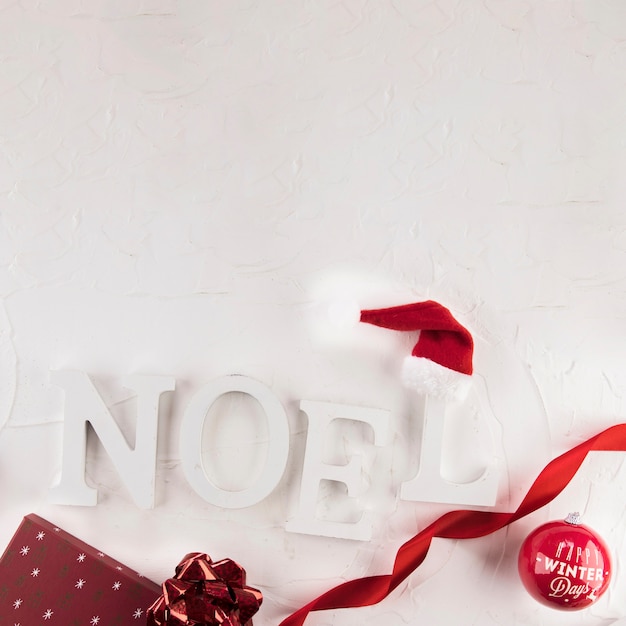 Noel inscripción cerca de bola de navidad y sombrero