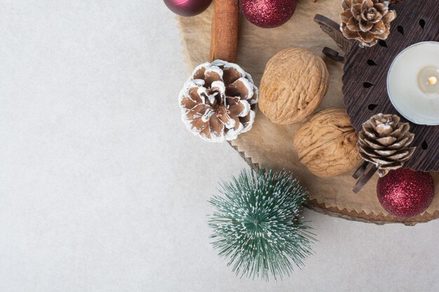 Nogal con piñas y bolas de Navidad en plato de madera. Foto de alta calidad