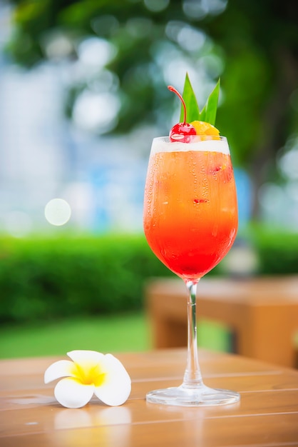 El nombre de la receta del cóctel mai tai o mai thai cóctel mundial incluye ron, jugo de limón, jarabe de orgeat y licor de naranja - bebida alcohólica dulce con flor en el jardín, concepto de vacaciones de relax