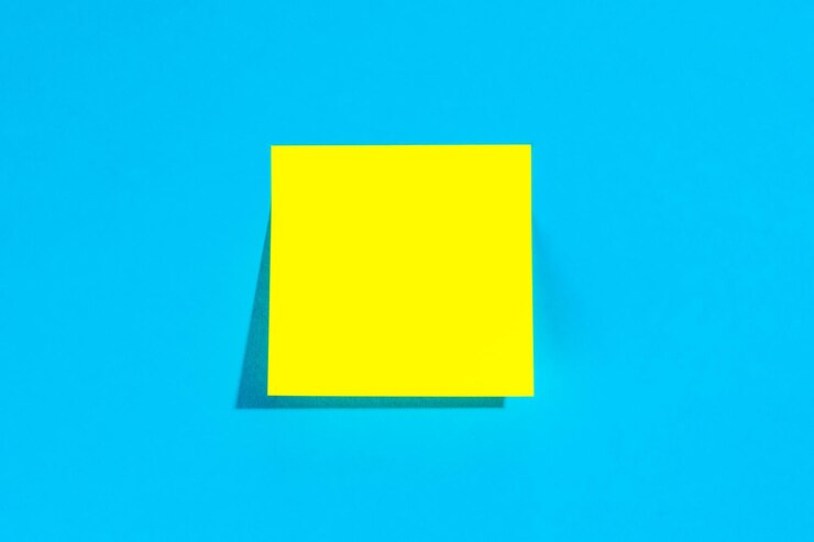 Foto gratuito nota amarilla con lugar vacío para texto sobre un fondo azul plano