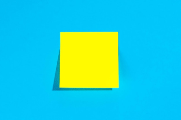 Nota amarilla con lugar vacío para texto sobre un fondo azul plano
