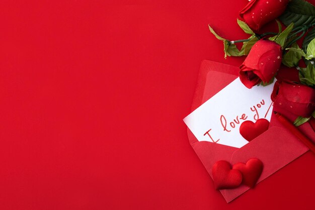 Nota que dice "Te amo" dentro de un sobre con corazones y rosas sobre fondo rojo.
