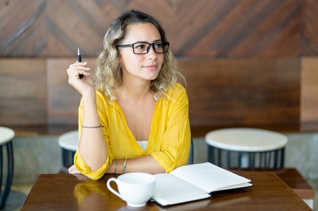 Notas de la escritura de la mujer joven bastante rizada para el proyecto de lanzamiento