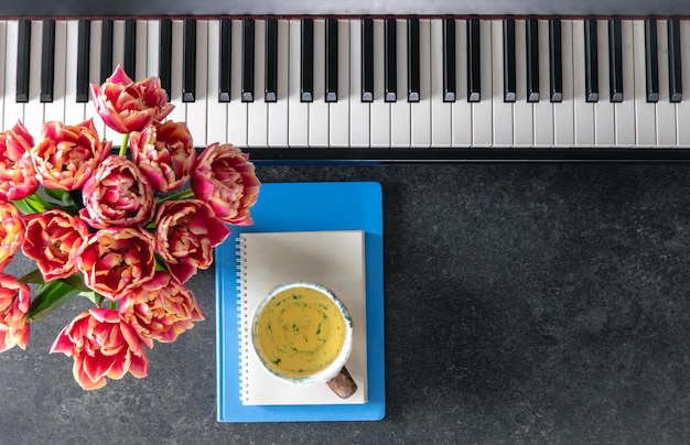 Las notas de flores de piano y una taza de té en un fondo oscuro vista superior