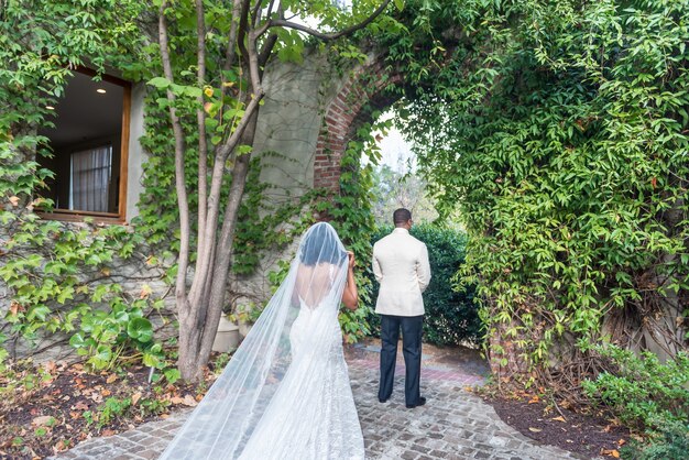 Novia acercándose al novio parado frente a un arco natural