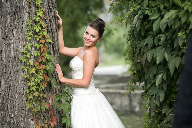 Novia apoyada en un árbol