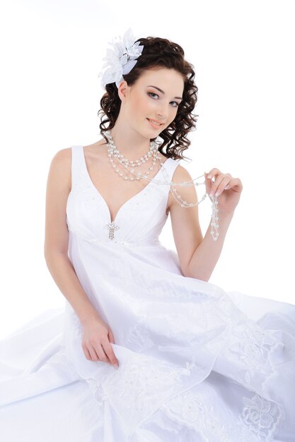 Novia de belleza en vestido de novia blanco con pelos rizados