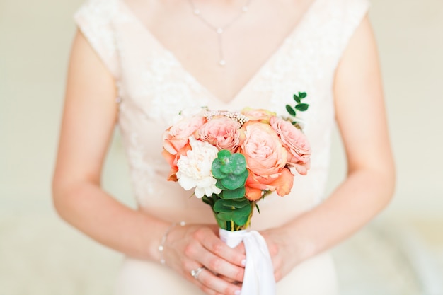 Novia de la boda que sostiene el ramo rosado de la flor.