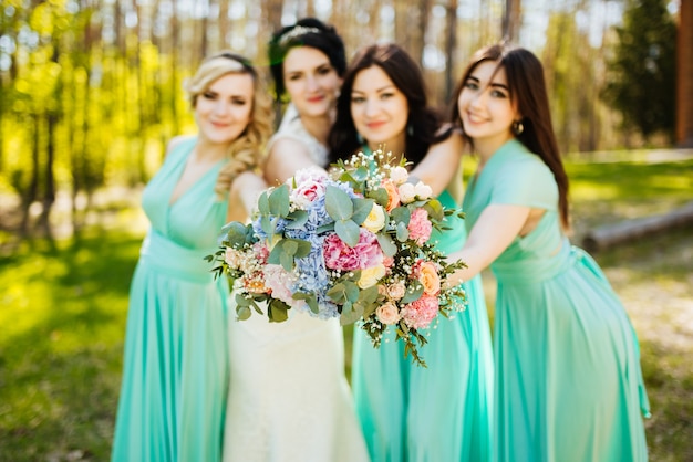 Novia y damas de honor con ramos de novia. Recepción soleada de la boda momento alegre.