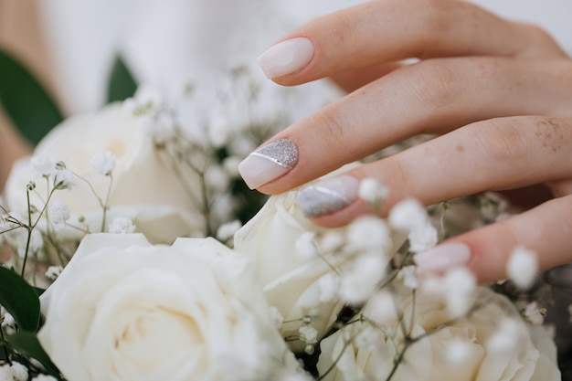 La novia demuestra su manicura sobre el ramo de la boda