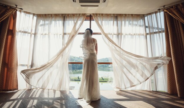 Novia se encuentra ante una ventana panorámica