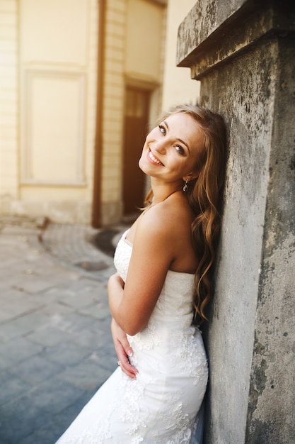 Novia feliz posando junto a un edificio de piedra