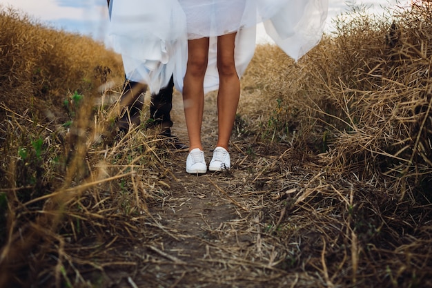 Novia en kedds blanco se encuentra en el campo