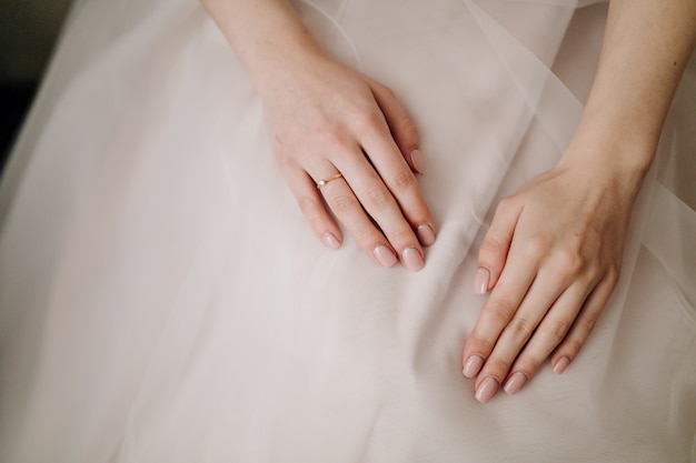 Novia manos con manicura en su vestido