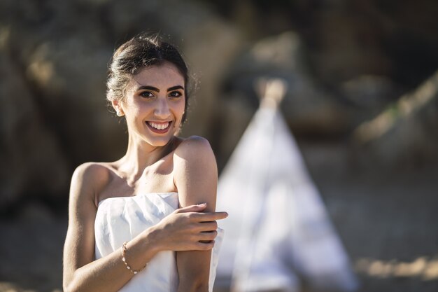 Novia morena caucásica sonriendo mientras posa en la playa