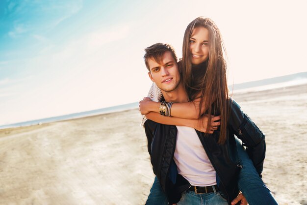 Novia y novio abrazando feliz. Joven bonita pareja de enamorados que datan en la primavera soleada a lo largo de la playa. Colores cálidos.