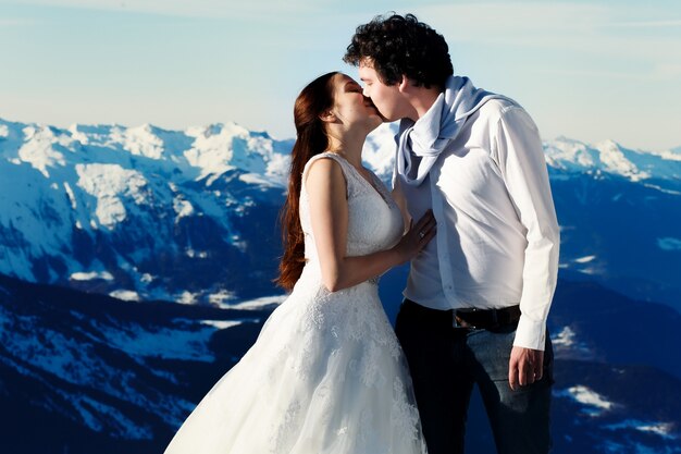 Novia y el novio en el amor besándose en el fondo de los Alpes Courchevel