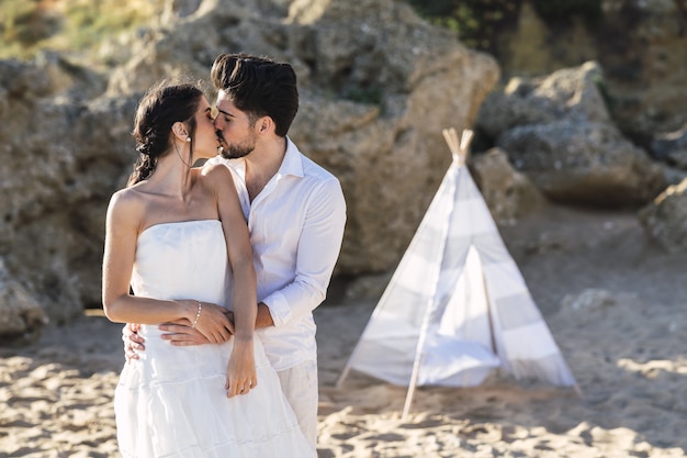 La novia y el novio besándose en la playa.